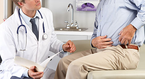 Doctor talking to a patient who is touching his mid section